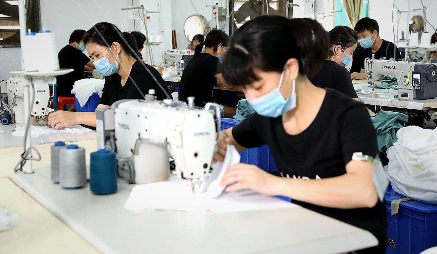 Sewing operators stitching fabric at industrial sewing machines in the pillow workshop