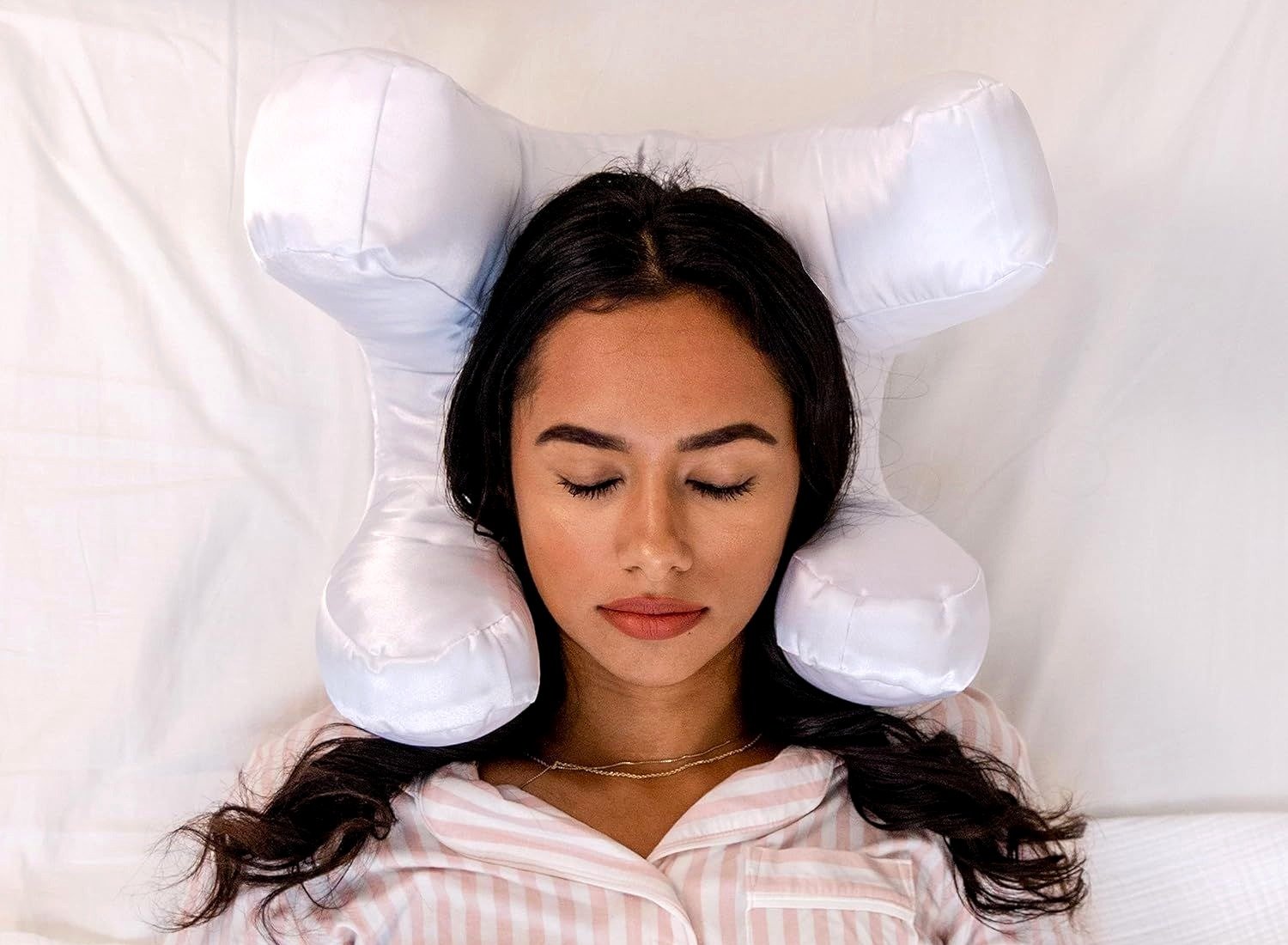 Woman resting on her back on the white satin face pillow, eyes closed, both cheeks clear of the fabric